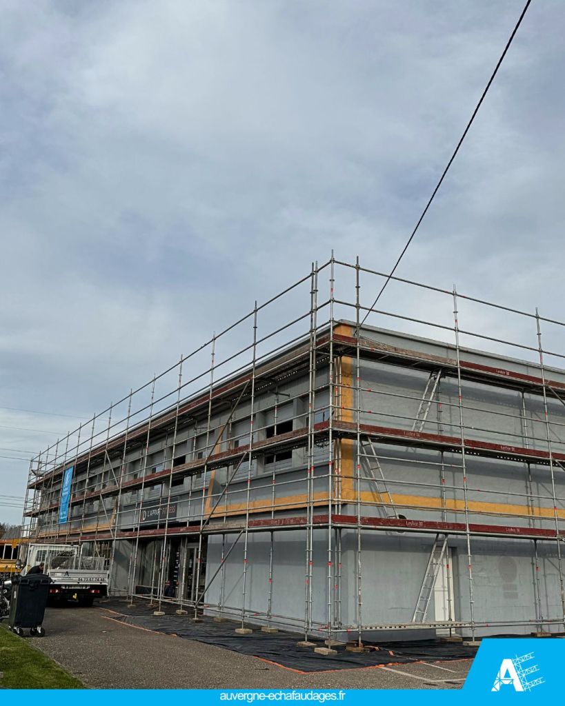 Vue d'un bâtiment en construction équipé d'échafaudages, montrant plusieurs niveaux de scaffolding autour de la structure.