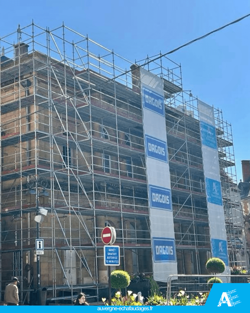 Un bâtiment en cours de rénovation, entouré d'échafaudages, avec des bâches publicitaires affichant le logo 'DAGUIS'.