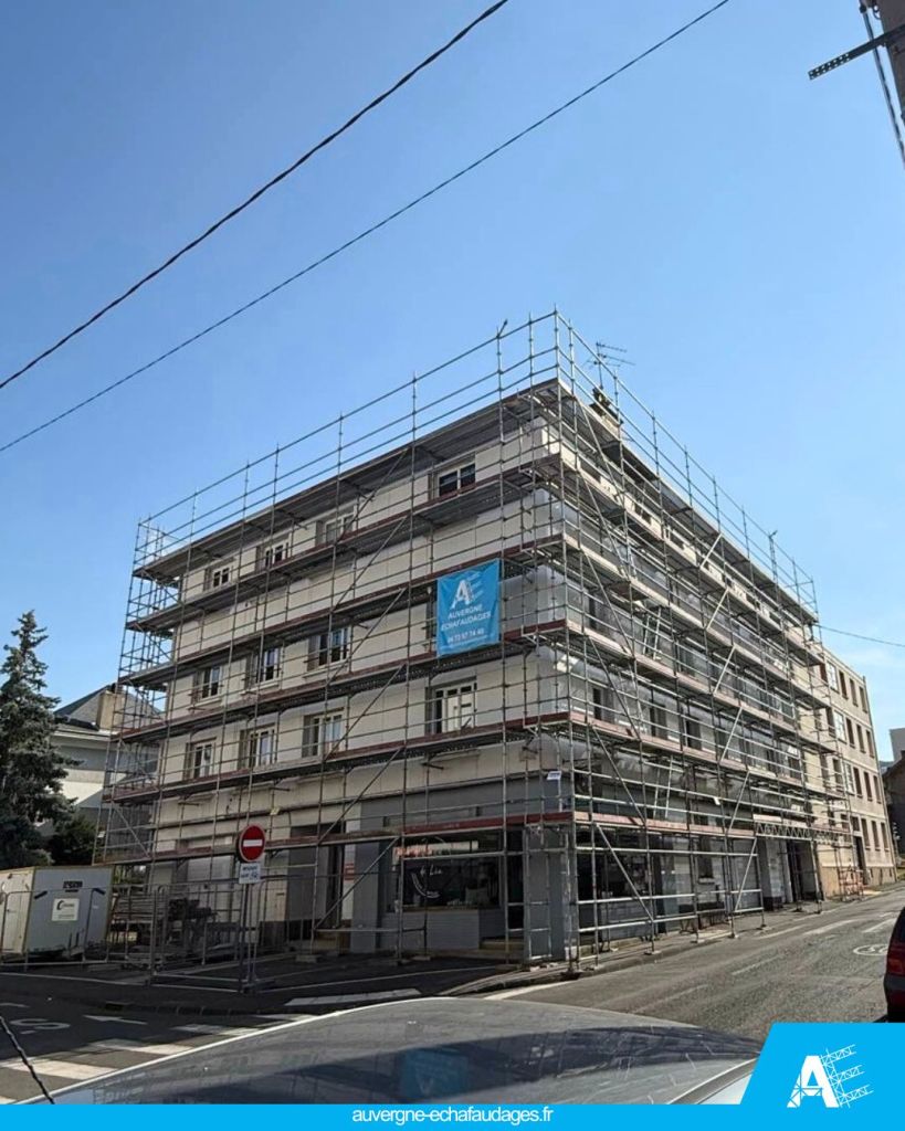 Bâtiment en cours de rénovation avec échafaudages sur toute la façade, sous un ciel bleu clair.